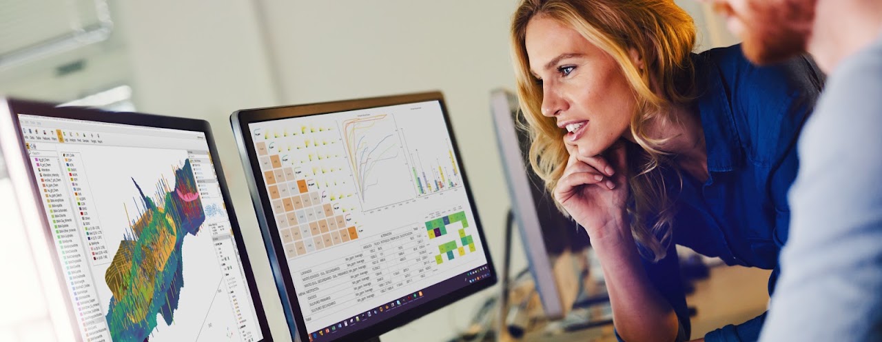 Two people reviewing a 3D block model and metallurgical charts on screen